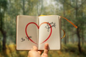 Offenes Notizbuch mit rotem Herz und den Worten Be You und Love Yourself